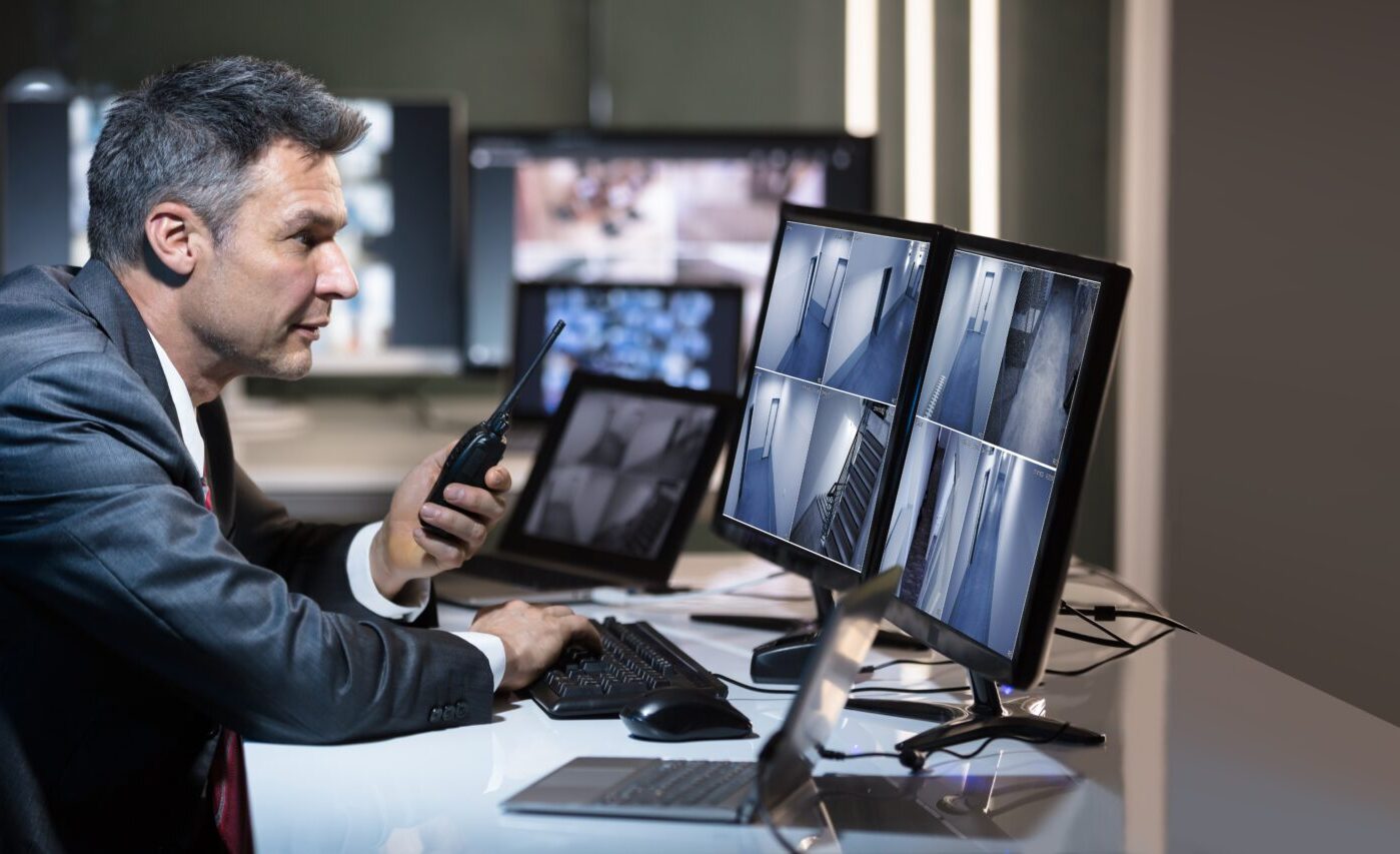 Businessman,Talking,On,Walkie,Talkie,While,Looking,At,Cctv,Camera